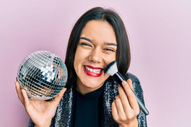 Parlak disko topu ve makyaj fırçası tutan genç İspanyol kız kahkahalarla gülüyor.. 