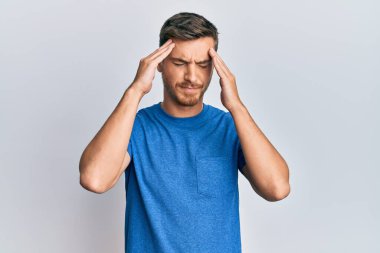 Yakışıklı, beyaz, günlük kıyafetler giyen, eli başının üstünde, stresten baş ağrısı çeken bir adam. migren ağrısı. 