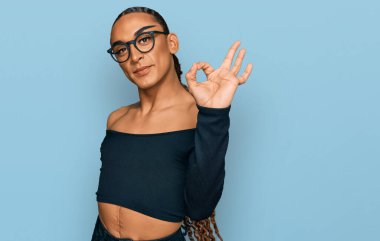 Makyaj yapan, uzun saçlı, gülümseyen kadın kıyafetleri giyen İspanyol transseksüel adam el ve parmaklarıyla imza atıyor. başarılı ifade. 