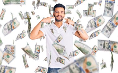 Gündelik kıyafetler giyen, neşeli gülümseyen, parmaklarıyla ve ağzıyla işaret eden genç, yakışıklı İspanyol adam. diş sağlığı kavramı.