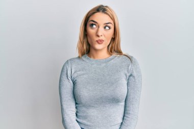 Gündelik giysiler giymiş genç beyaz kadın gülümseyip yan tarafa bakıyor ve düşünüyor.. 