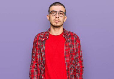 Günlük kıyafetler giyen İspanyol genç adam yüzünde ciddi bir ifadeyle rahatladı. Basit ve doğal bir şekilde kameraya bakıyorsun.. 