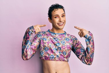 Makyaj elbisesi giyen, neşeli gülümseyen, parmaklarıyla ve ağzıyla işaret eden yakışıklı bir adam. diş sağlığı kavramı. 