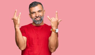 Orta yaşlı yakışıklı, sıradan kıyafetler giymiş çılgın bir ifadeyle bağıran elleri havada rock sembolü yapan bir adam. Müzik yıldızı. ağır kavram. 