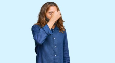 Uzun saçlı, sakallı, sıradan kıyafetler giyen, burnu ve gözleri ovuşturan yorgun, bitkin ve baş ağrısı çeken çekici bir adam. Stres ve hüsran kavramı. 