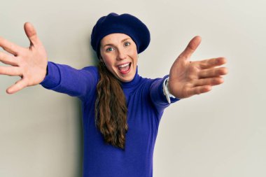 Bere takmış genç sarışın kadın kameraya sarılıp gülümsüyor. Mutluluğu kucaklayan neşeli bir ifade.. 