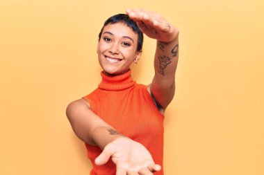 Sıradan kıyafetler giymiş genç bir kadın kameraya bakıyor ve sarılmak için kollarını açmış gülümsüyor. Mutluluğu kucaklayan neşeli bir ifade.. 