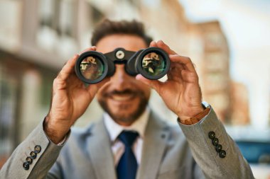 Orta yaşlı işadamı şehirde dürbünle yeni fırsatlar arıyor..