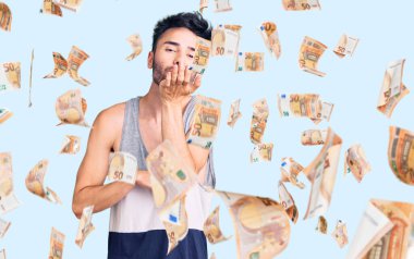 Gündelik giysiler giymiş genç İspanyol bir adam kameraya bakıp havada bir öpücük savuruyor ve sevimli ve seksi oluyor. aşk ifadesi.