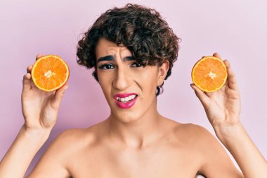 Şok olmuş suratında taze portakal tutan genç adam, şüpheci ve alaycı görünüyor, ağzı açık kalınca şaşırıyor. 