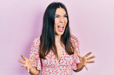 Genç esmer kadın yaz elbisesi giyiyor. Deli gibi bağırıyor, agresif bir ifade ve kollarla bağırıyor. hüsran kavramı. 