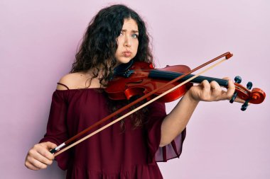 Kıvırcık saçlı, keman çalan komik yüzlü esmer müzisyen kadın. Ağzı havayla şişer, havayı yakalar.. 