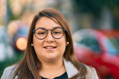 Latin kökenli genç ve iri yarı bir iş kadını şehirde mutlu mesut dikiliyor..