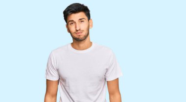 Gündelik beyaz tişört giyen, komik yüzlü, yanak şişiren genç yakışıklı adam. Havayla şişmiş ağız, çılgın bir ifade.. 