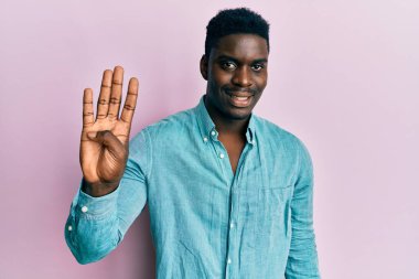 Yakışıklı, sıradan kıyafetler giyen, dört numarayı gösterip işaret eden, kendinden emin ve mutlu bir şekilde gülümseyen siyahi adam.. 