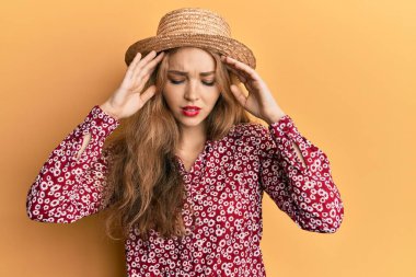 Güzel sarışın, beyaz kadın, stres yüzünden kafasında ağrı olsun diye el ele tutuşan yaz şapkası takıyor. migren ağrısı. 