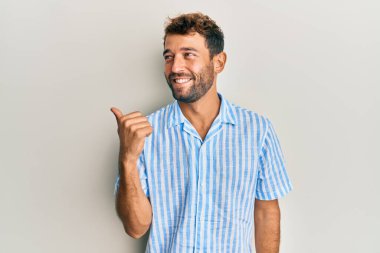 Sakallı, sıradan tişörtlü yakışıklı, baş parmağını kaldırmış, ağzı açık gülümsüyor. 