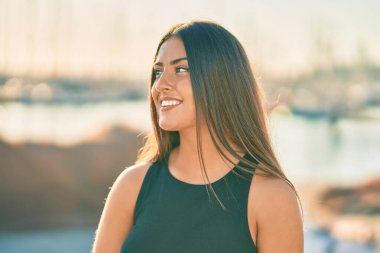 Genç İspanyol kız gülümseyerek şehirde mutlu mesut dikiliyor..