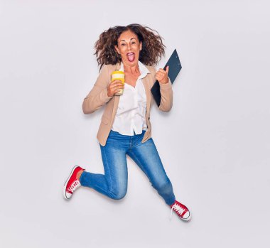 Zarif kıyafetler giyen genç ve güzel İspanyol iş kadını bunu ağzıyla kutluyor. Bir fincan kahve ve panoyu izole edilmiş beyaz arka planda tutarken heyecanlandım.