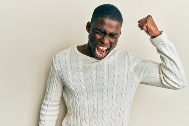 Genç, Afro-Amerikan bir adam, günlük kıyafetler giyiyor kızgın ve kızgın. Öfkeyle bağırırken yumruğunu kaldırıyor. öfke ve agresif konsept. 