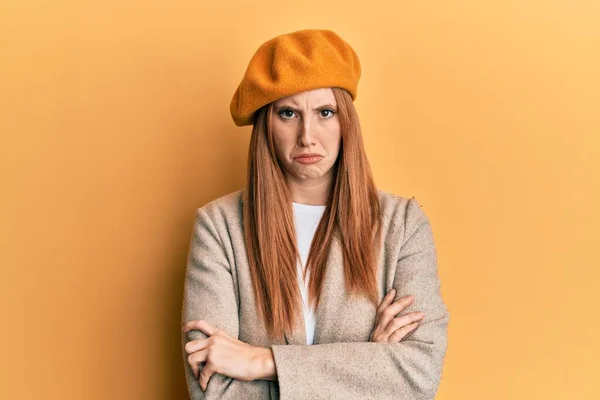 Young irish woman wearing french look with beret skeptic and nervous, disapproving expression on face with crossed arms. negative person.