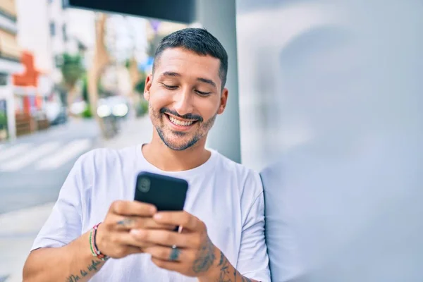 Duvara Dayanmış Akıllı Telefon Kullanan Mutlu Gülümseyen Genç Spanyol Adam — Stok fotoğraf