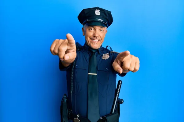 Handsome middle age mature man wearing police uniform pointing to you and the camera with fingers, smiling positive and cheerful