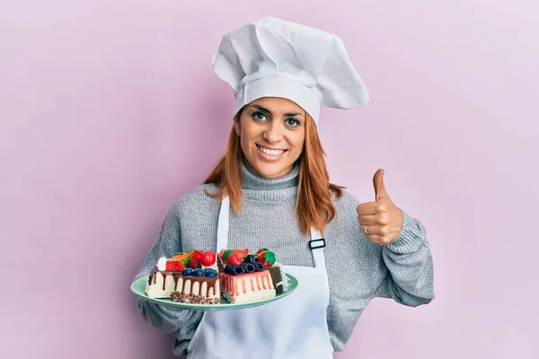 Hispanic Young Chef Woman Holding Cake Slices Smiling Happy Positive — 图库照片