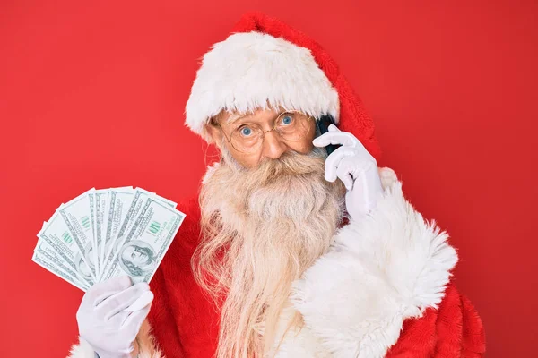 Old Senior Man Wearing Santa Claus Costume Holding Dollars Smartphone — Stock Photo, Image