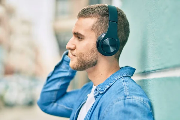 Νεαρός Καυκάσιος Άνδρας Χαμογελά Χαρούμενος Χρησιμοποιώντας Ακουστικά Στην Πόλη — Φωτογραφία Αρχείου