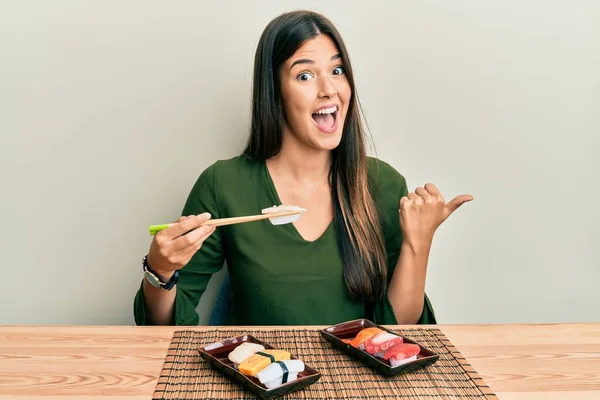 Young Brunette Woman Eating Sushi Sitting Table Pointing Thumb Side — Stock Photo, Image