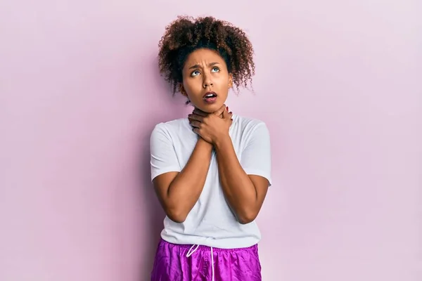 Beautiful african american woman with afro hair wearing sportswear shouting and suffocate because painful strangle. health problem. asphyxiate and suicide concept.