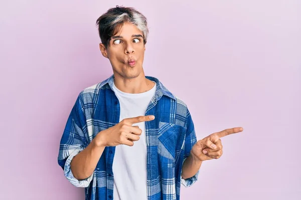 Young Hispanic Man Pointing Fingers Side Making Fish Face Mouth — Stock Photo, Image