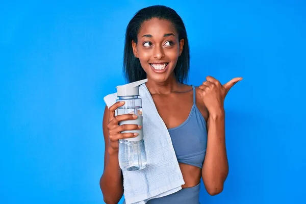 Молодая Африканская Американка Спортивной Одежде Пьет Бутылку Воды Указывая Пальцем — стоковое фото