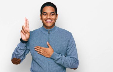 Genç, yakışıklı, sıradan bir eşofman üstü giyen, elleri göğsünde, parmakları havada küfreden, sadakat yemini eden genç bir İspanyol. 