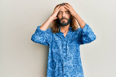 Uzun saçlı ve sakallı çekici bir adam. 80 'lerin disko tarzı tişörtü giyiyor. Baş ağrısı çekiyor. Eller başının üstünde.. 