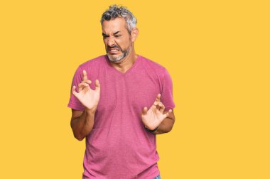 Orta yaşlı, gri saçlı, günlük kıyafetler giyen, tiksindirici, tiksindirici, tiksindirici bir yüz ifadesi takınan bir adam.. 