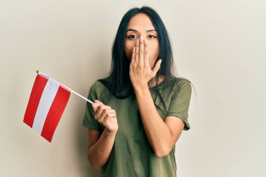 Genç İspanyol kız elinde Avusturya bayrağıyla ağzını eliyle kapatıyor, şokta ve hata yapmaktan korkuyor. şaşırmış ifade 