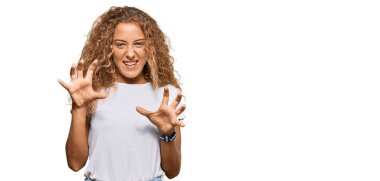 Güzel beyaz tişört giyen beyaz kız komik bir şekilde gülüyor kedi gibi pençe hareketi yapıyor, agresif ve seksi bir ifade. 