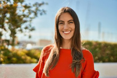 Genç İspanyol kadın gülümseyerek şehirde mutlu mesut dikiliyor..