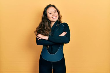 Dalgıç neoprene üniforması giyen genç İspanyol kız kameraya bakarken kollarını kavuşturup gülümsüyor. pozitif kişi. 