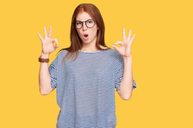 Gündelik giysiler ve gözlük takan genç bayan şaşırmış ve şok olmuş görünüyor. çılgın ifade 