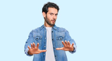 Günlük kıyafetler giyen genç İspanyol bir adam. El hareketlerini, avuç içleriyle durduruyor. Öfkeli ve hayal kırıklığına uğramış bir ifade. 