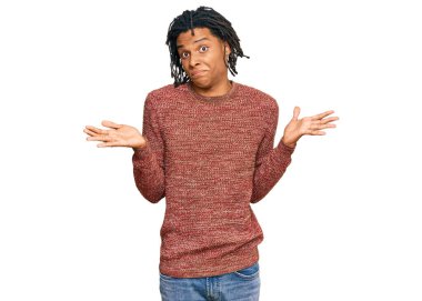 Sıradan bir kazak giyen, elleri ve kolları havada, kafası karışmış genç Afro-Amerikan bir adam. şüphe kavramı. 