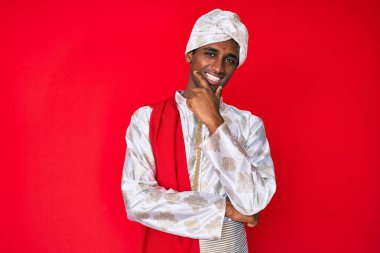 Geleneksel Sherwani elbisesi giyen yakışıklı Hintli adam kameraya kendinden emin bakıyor kollarını kavuşturmuş ve çenesini kaldırmış gülümsüyor. Olumlu düşünmek. 