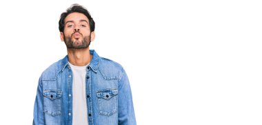 Latin asıllı genç bir adam, günlük giysiler içinde kameraya bakıyor ve güzel ve seksi bir şekilde havadan öpücük yolluyor. aşk ifadesi. 