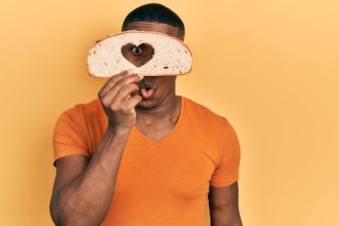 Genç siyah adam elinde kalp şeklinde ekmek tutuyor. Şaşırtmak için ağzı açık kalmış, korkmuş ve şaşırmış. İnanmayan yüz. 