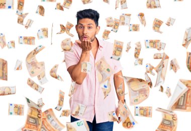 Yakışıklı Latin Amerikalı sıradan bir yaz gömleği giyen genç adam kameraya bakıp havada bir öpücük savuruyor. Güzel ve seksi. aşk ifadesi.