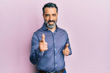 Orta yaşlı, sakallı, gri saçlı, iş kıyafetleri giyen mutlu ve komik yüzlü bir adam. iyi enerji ve titreşimler. 