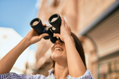 Şehirde dürbünle gülümseyen genç İspanyol kız..